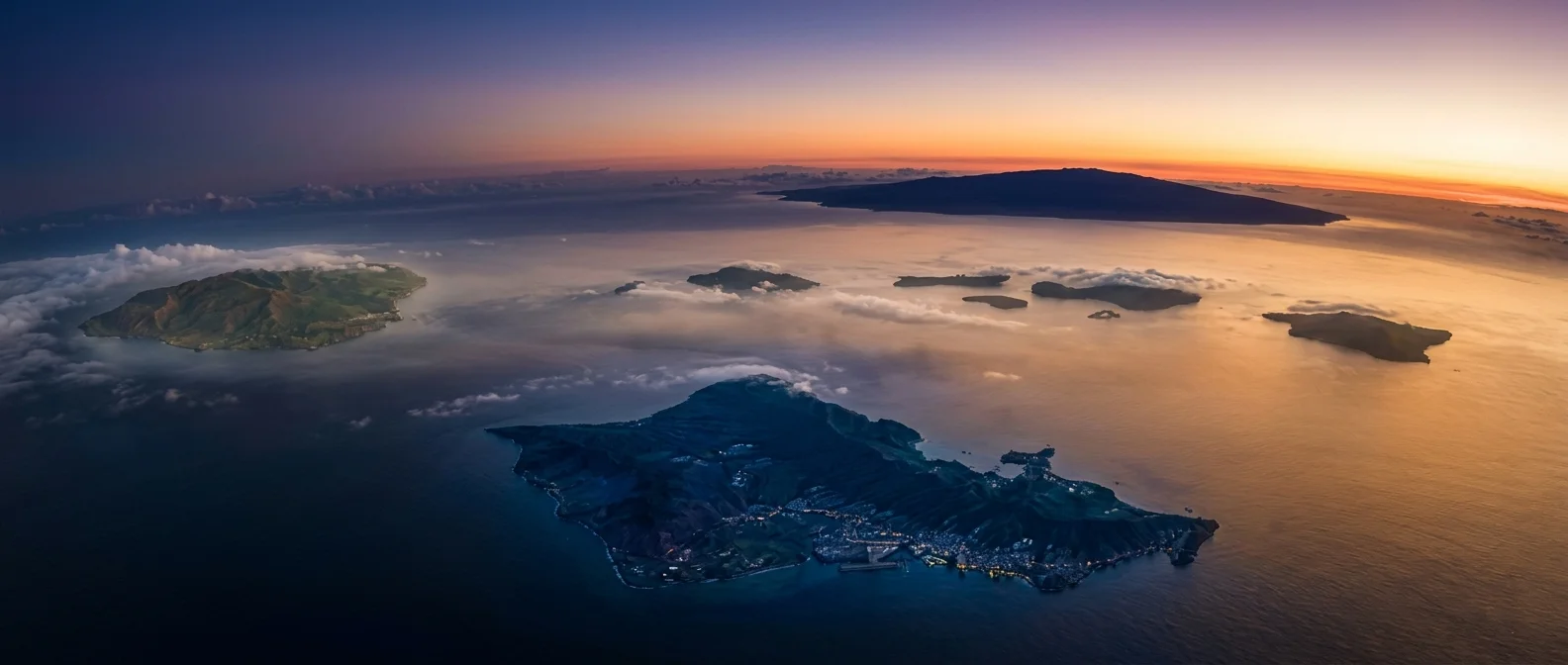 Aerial view of the Hawaiian islands at dusk, an island's lights in the foreground